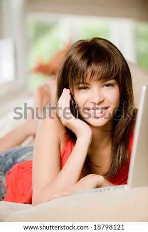 A woman at home on the sofa with laptop computer and phone