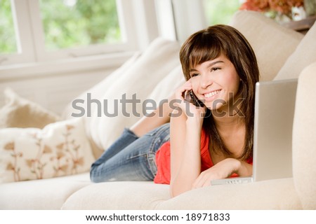 A woman at home on the sofa with laptop computer and phone