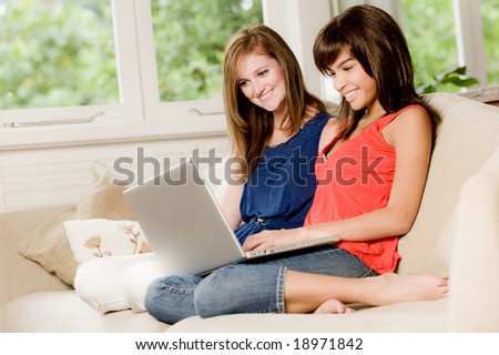Two young woman at home on the sofa with laptop
