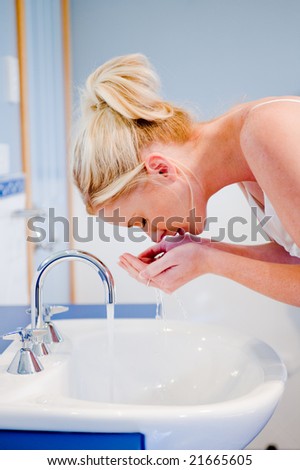 A young attractive woman washing her face in the bathroom