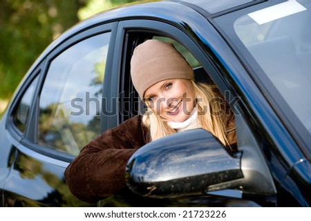 A young woman sitting in drivers seat of a saloon car