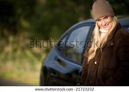A young woman standing next to her saloon car
