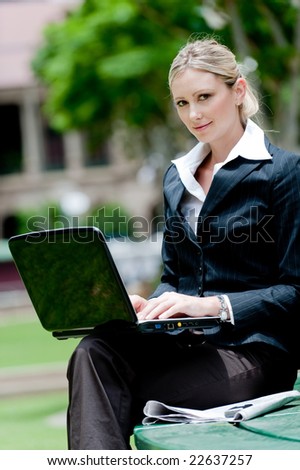 A young professional woman sitting outside with laptop computer
