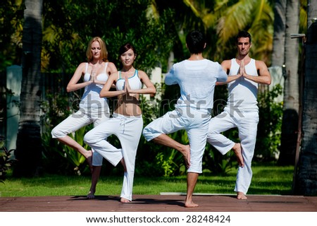 A small group of adults attending a yoga class outside in a tropical setting