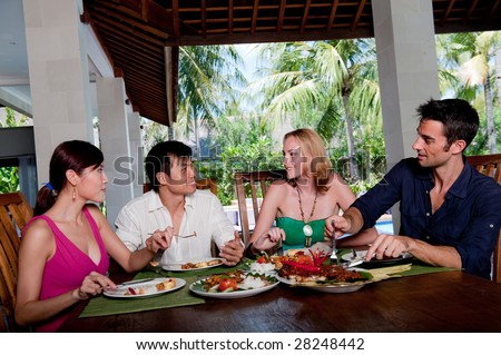 A group of four adults enjoying lunch at their villa on vacation
