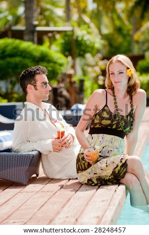 An attractive couple having drinks by the pool on vacation