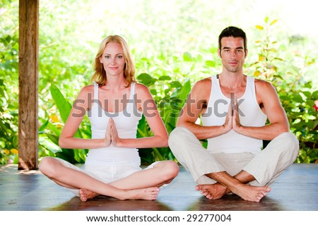 An attractive couple practicing yoga outdoors