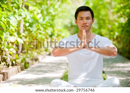 A young Chinese man meditating outside