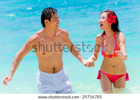 An attractive Asian couple in the sea playing around