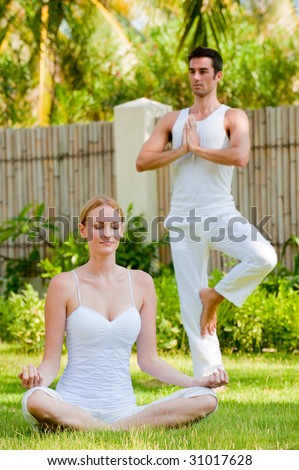 A couple practising yoga outside in the garden