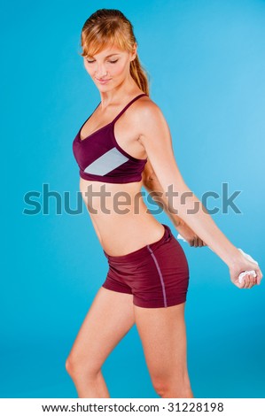 An attractive toned woman in sportswear stretching with a towel on blue background
