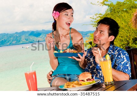 An attractive couple eating lunch outside on tropical island