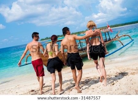 Four friends walking towards their dive boat waiting for them in crystal blue ocean