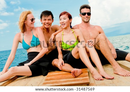 Four friends sitting on a wooden dive boat in the ocean