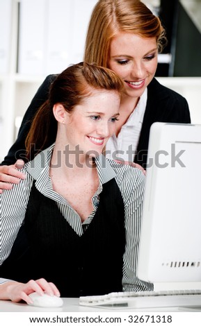 Two attractive businesswomen discussing work in front of a computer in the office