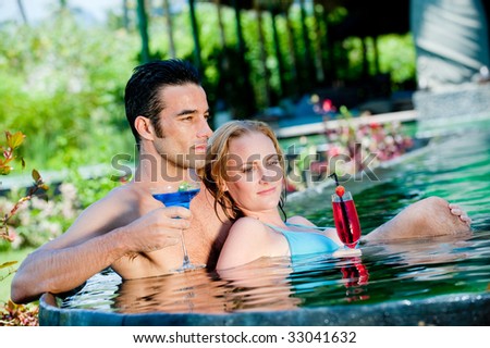 A couple with drinks in the pool on vacation