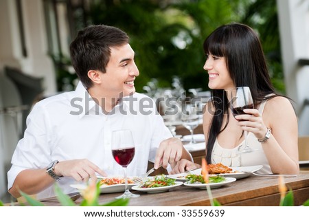 A young and attractive couple dining together in an outdoor restaurant
