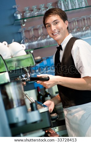 A young and attractive barista making a coffee in an indoor restaurant