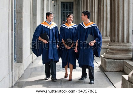 A group of graduates holding their mortar board in their hands and chatting along a hallway