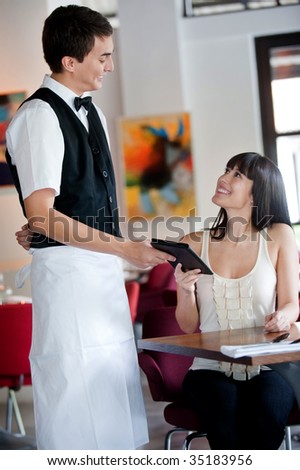 A young and attractive woman paying the bill in a restaurant