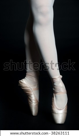 A pair of slender ballerina legs on tip toe against black background