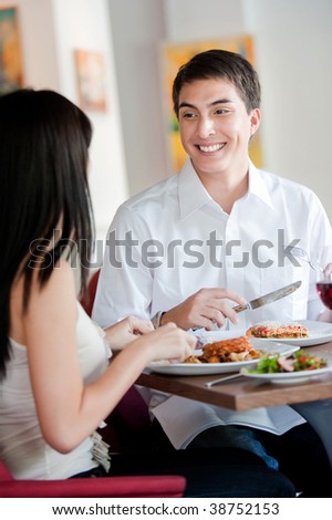 A young and attractive man dining with his partner in an indoor restaurant