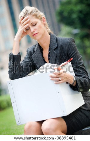 A depressed and worried looking businesswoman holding a box of her belongings after being fired