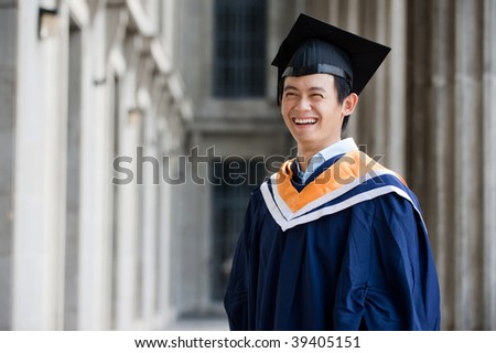A young graduate in graduation attire standing in a hallway