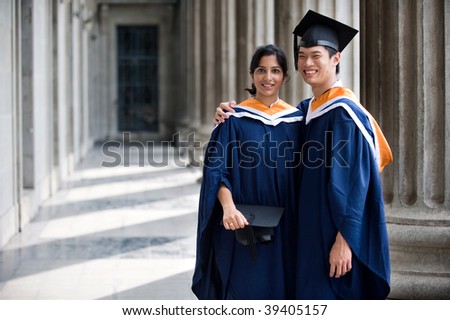 Two young graduates standing in a hallway with their mortar boards