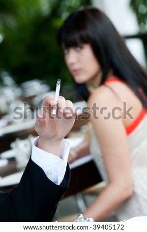 A young and attractive woman irritated by the smoke from a cigarette at an outdoor dining area