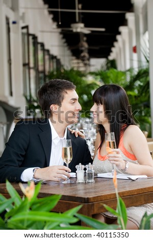 An attractive young couple shares a salad at an outdoor restaurant