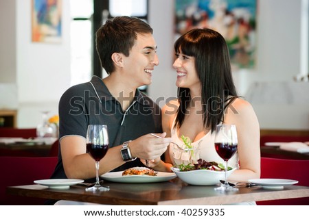 A young and attractive couple dining together in an indoor restaurant