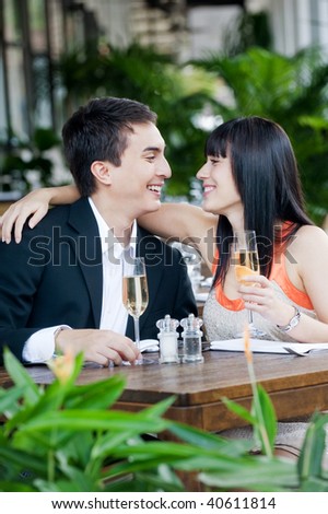 An attractive young couple shares a salad at an outdoor restaurant