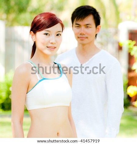 An attractive and healthy asian couple standing outdoors in a garden