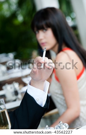 A young and attractive woman irritated by the smoke from a cigarette at an outdoor dining area