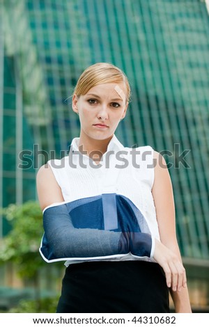 A young businesswoman with injured arm and band-aid standing in the city