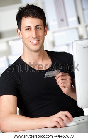 A good looking man doing an online payment at home using his credit card