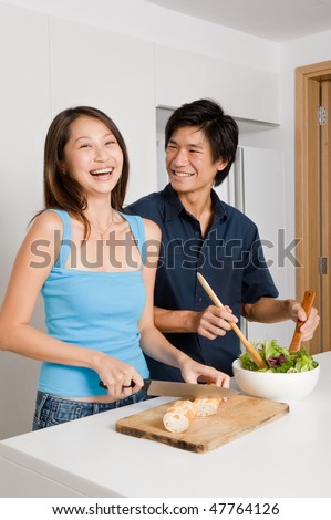 A good looking couple preparing a meal of bread and salad in the kitchen at home