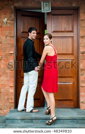 An attractive dressed-up couple at an entrance outdoors