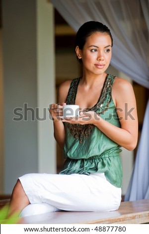An attractive young woman having a drink and relaxing indoors
