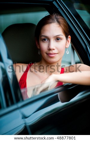 An attractive well-dressed lady stepping out of a stylish car outdoors