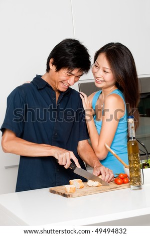 A good looking couple preparing a meal of bread and salad in the kitchen at home