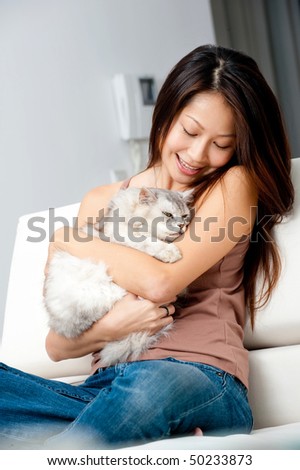 A good looking woman holding up her pet cat in her home