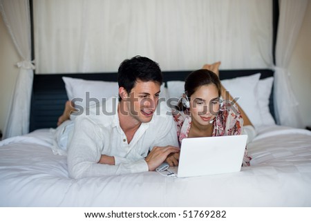 An attractive caucasian couple making a video call on a laptop in their bedroom