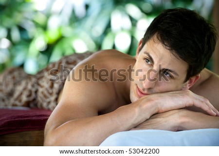 An attractive caucasian man lying down on a massage bed at a spa