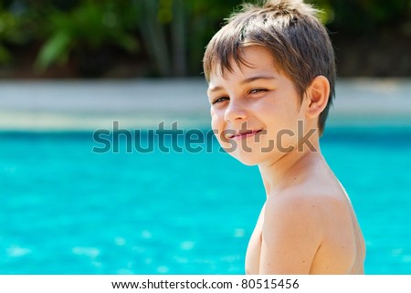 Happy young smiling boy by the pool