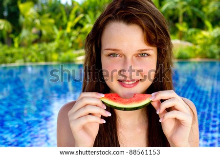 An young and attractive woman eating watermelon by the pool