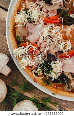 Styled pizza with vegetable and meat on wooden table