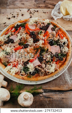 Styled pizza with vegetable and meat on wooden table