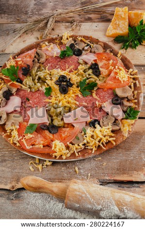 Pizza with bacon and meat on wooden table. Vertical top view